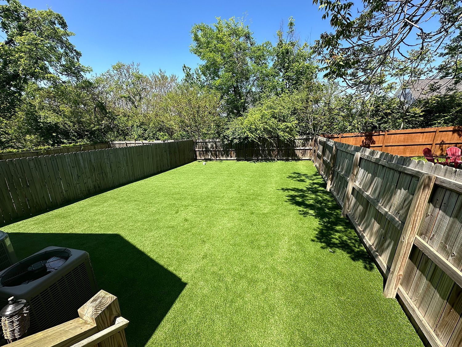 A backyard with a wooden fence and a lush green lawn