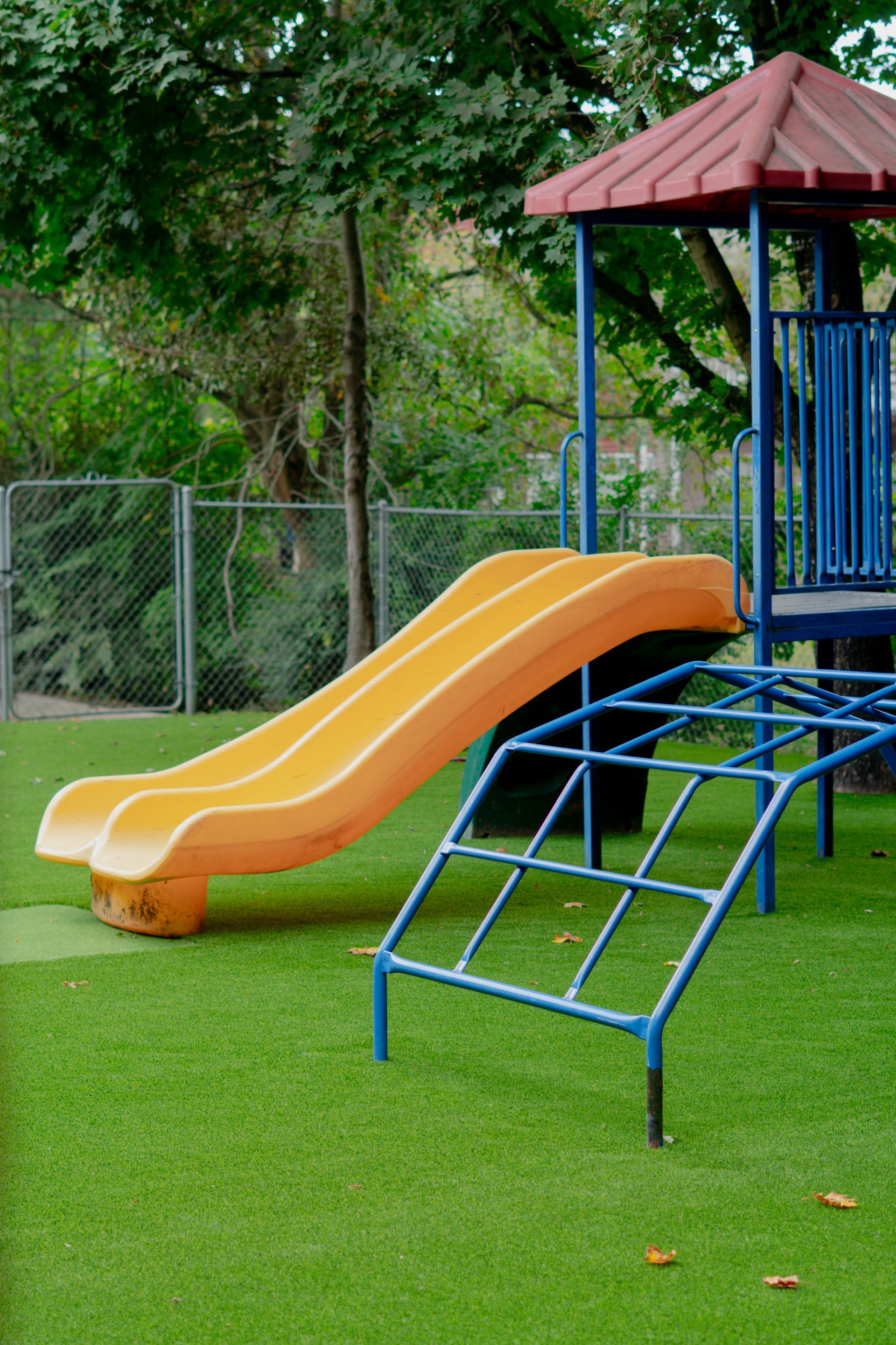 Playground slide and climbing structure on green turf.