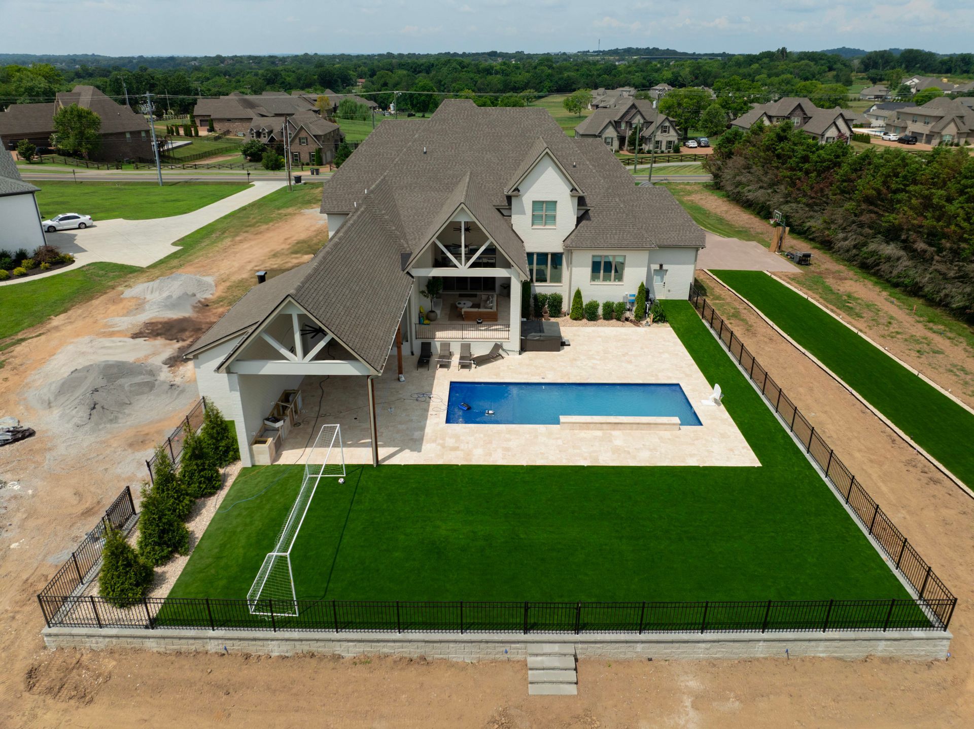 Large white house with a pool and artificial turf.