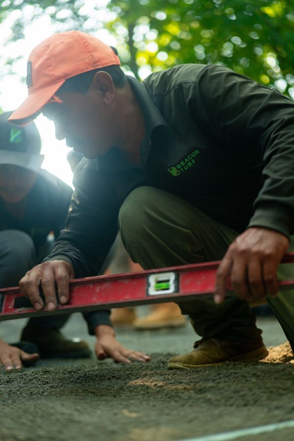 A man wearing orange hat using a level on a surface, outdoors.