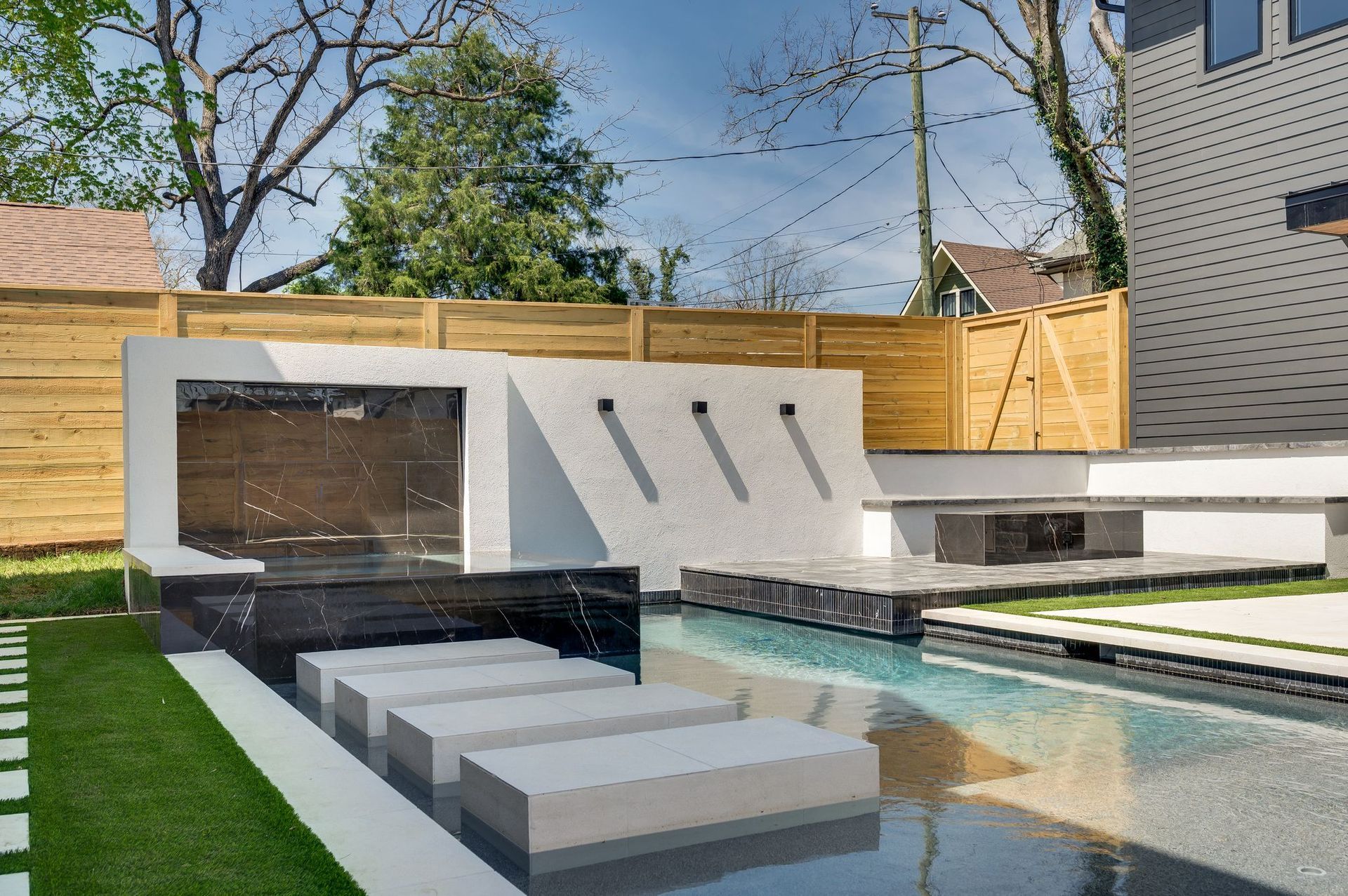 A modern backyard with a swimming pool and a wooden fence.
