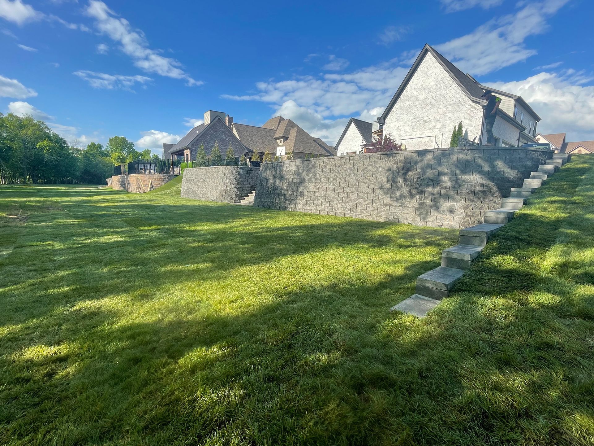 Stone buildings on a grassy hill under a blue sky with clouds.