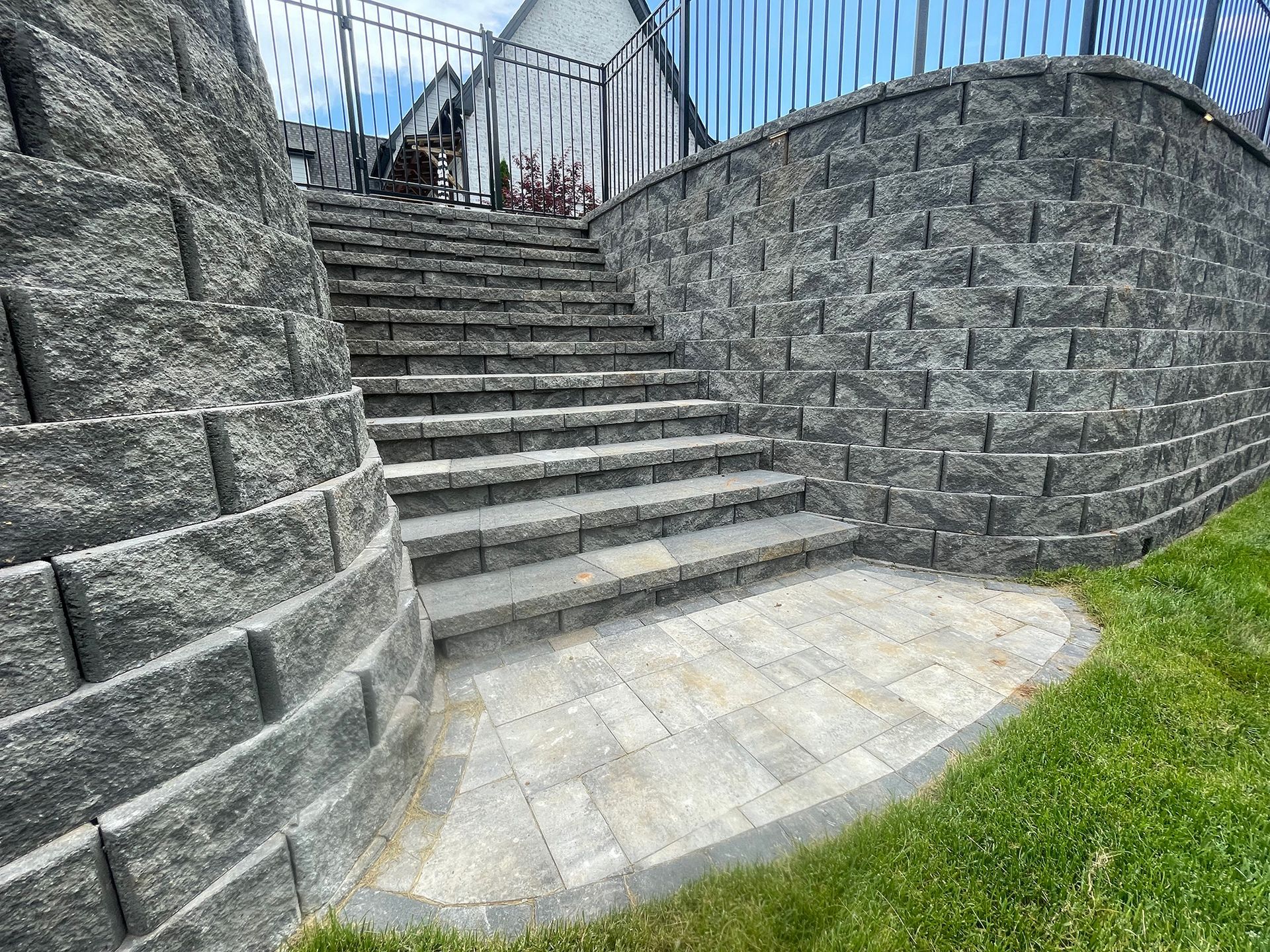 Stone steps lead up a tiered landscape with retaining walls and a grassy area.