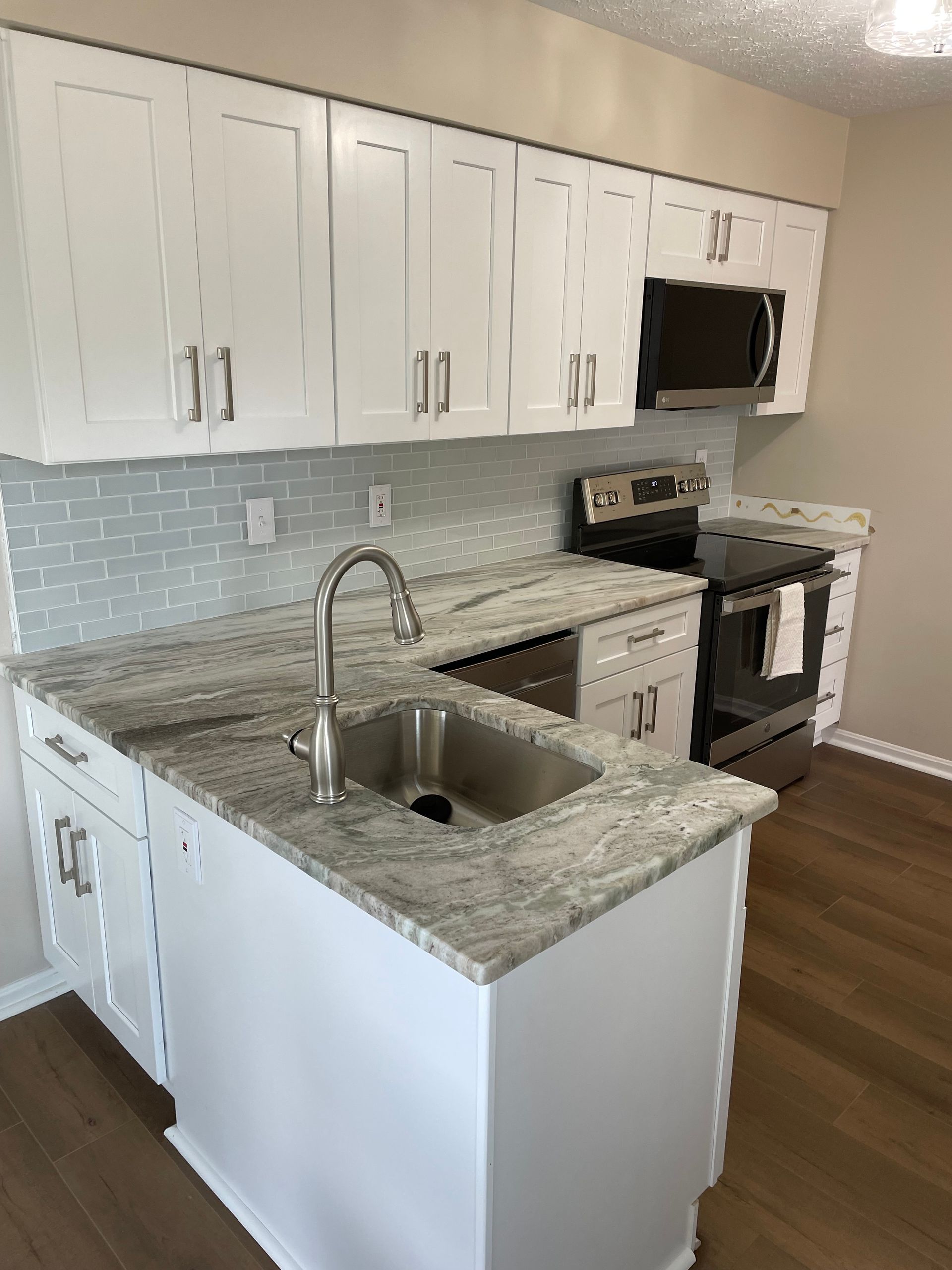 White kitchen with granite countertops, stainless steel sink, and appliances.