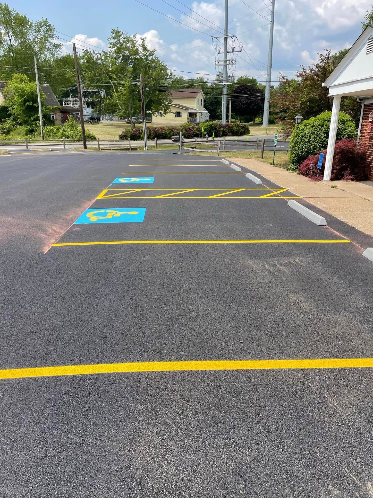 Two handicapped parking spaces marked with blue symbols and yellow painted lines in an asphalt parking lot.
