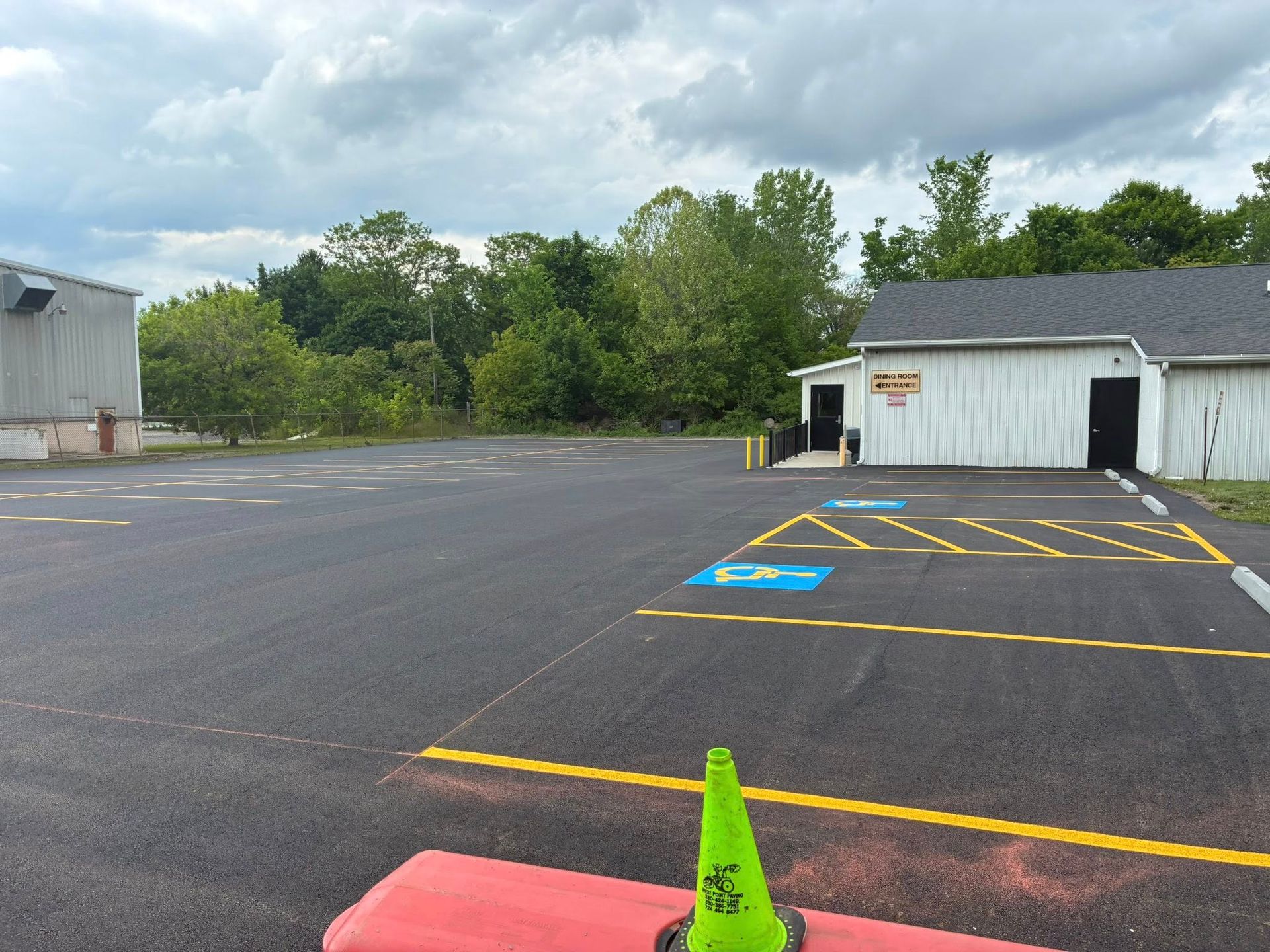 Empty parking lot with a handicap accessible space marked by blue paint and yellow lines near a white commercial building.