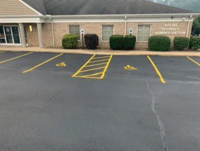 Two handicap parking spaces with a marked access aisle in front of a Social Security Administration office building.