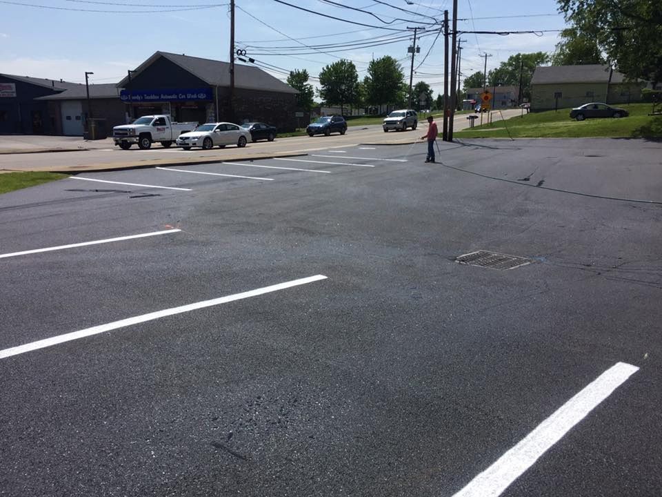 An asphalt parking lot with freshly painted white parking space lines and a person standing in the distance.
