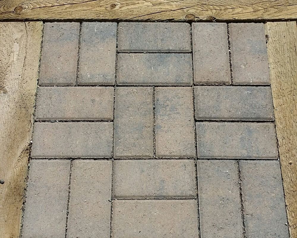 Pavers in a running bond pattern, bordered by wood.