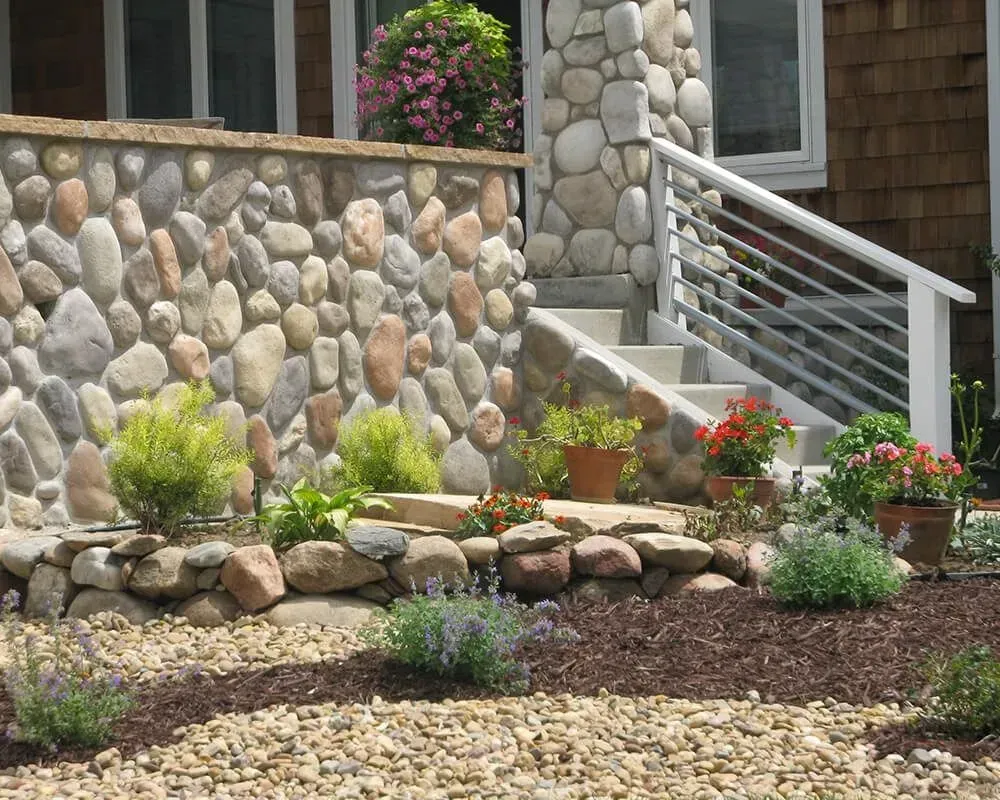 Stone facade with steps, landscaping, and plants in front of a building.