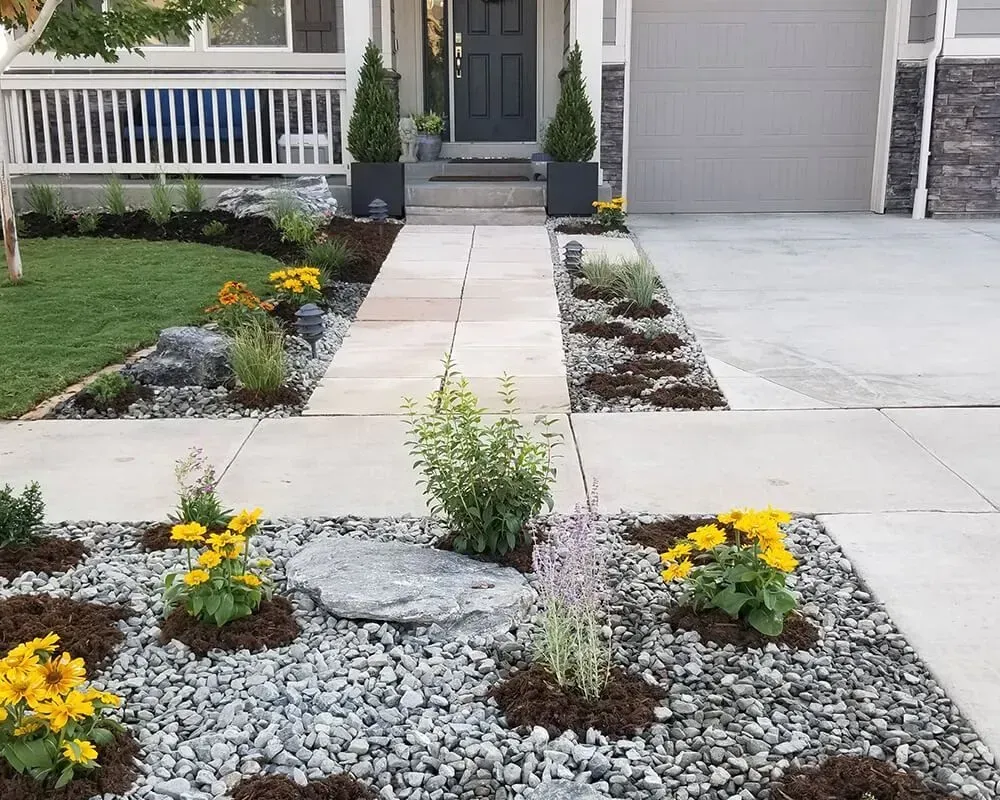 Landscaped front yard with gray gravel beds, flowers, and path leading to a gray door.