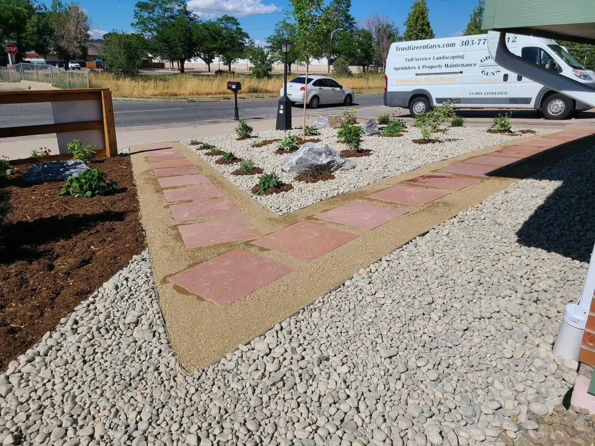 Landscaped front yard with brick path and gravel, small plants, and a parked van.