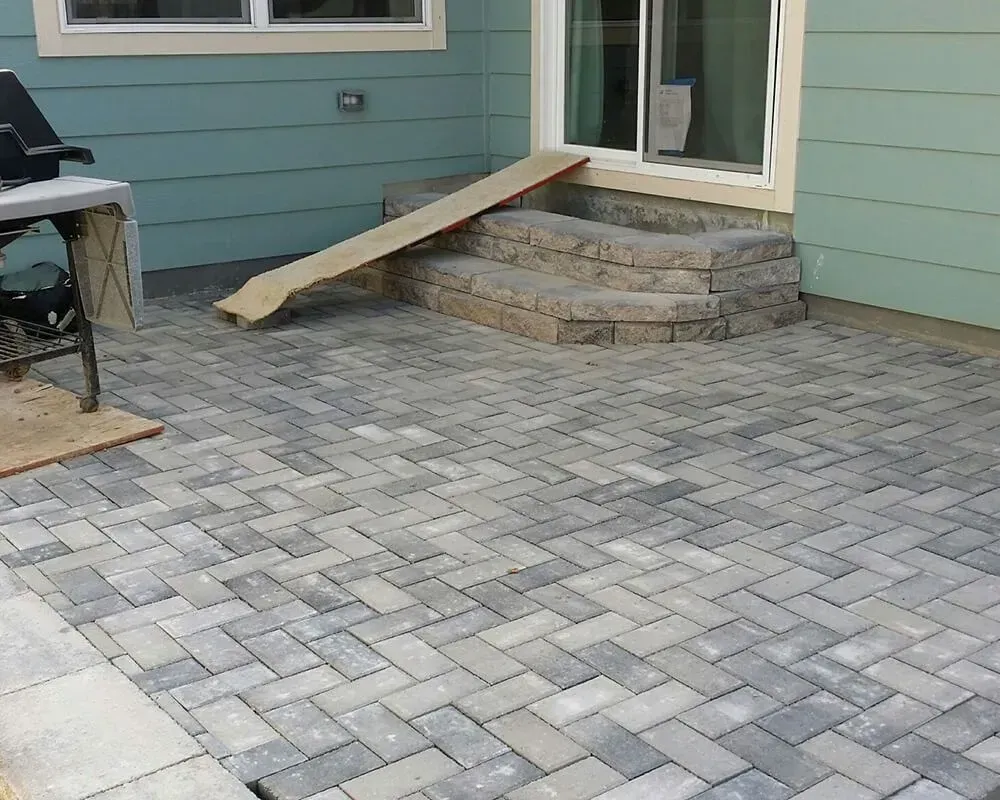 A brick patio with stairs and a ramp leading to a sliding glass door.