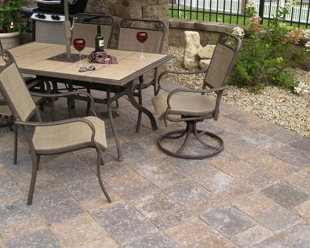 Patio with table, chairs, wine, and brick pavers.