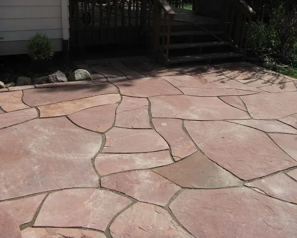 Flagstone patio leading to wooden deck steps.