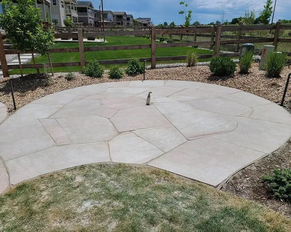 Circular stone patio with landscaping in a residential area.