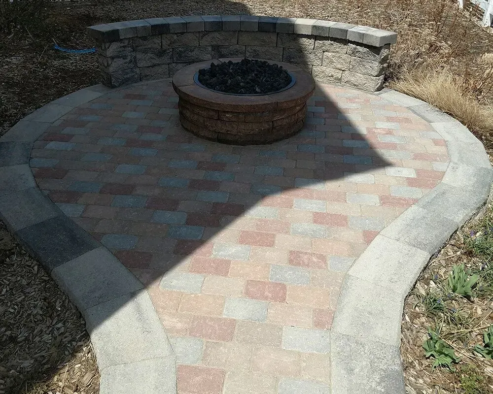 Brick patio with fire pit, surrounded by a low stone wall.