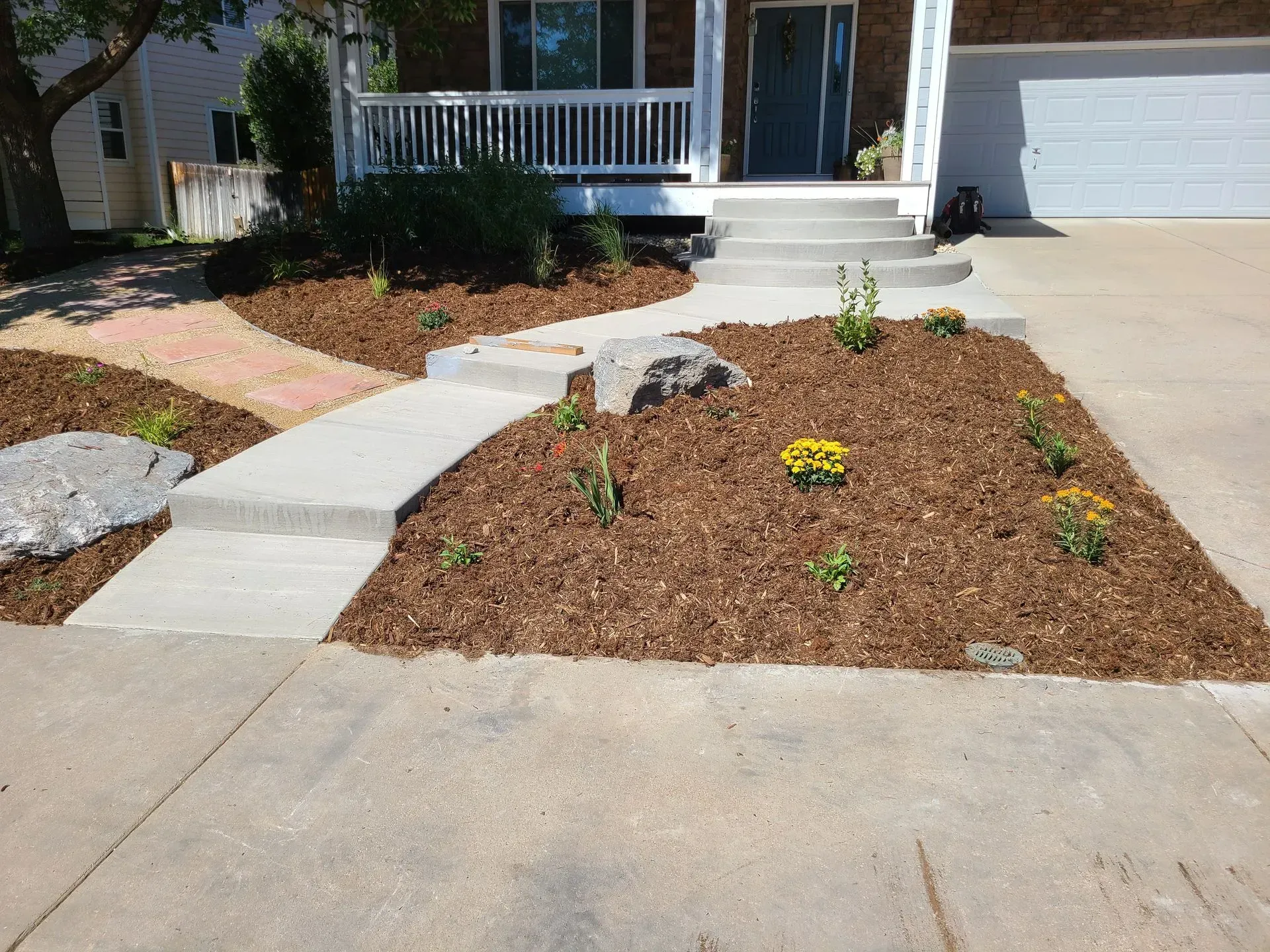 Pathway and flowerbeds with fresh mulch in front of a house.