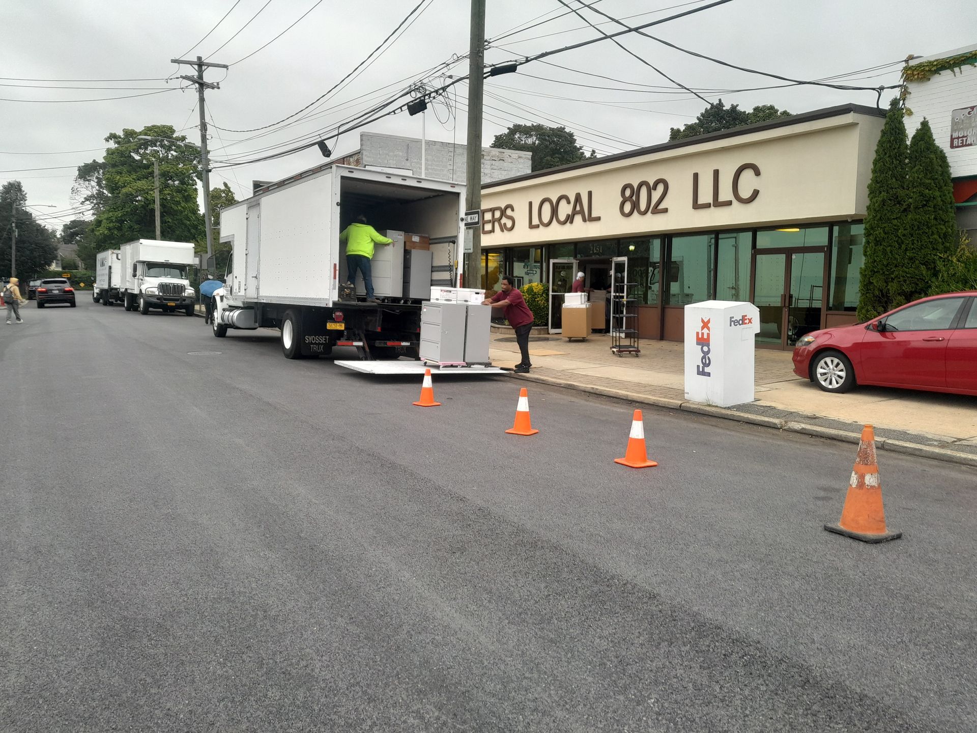 Trucks unloading supplies in front of a building,