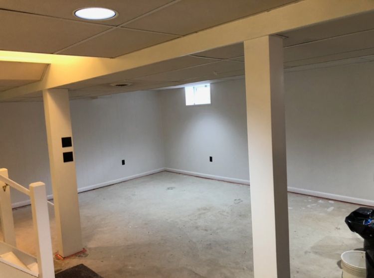 An empty basement with white walls and a small window