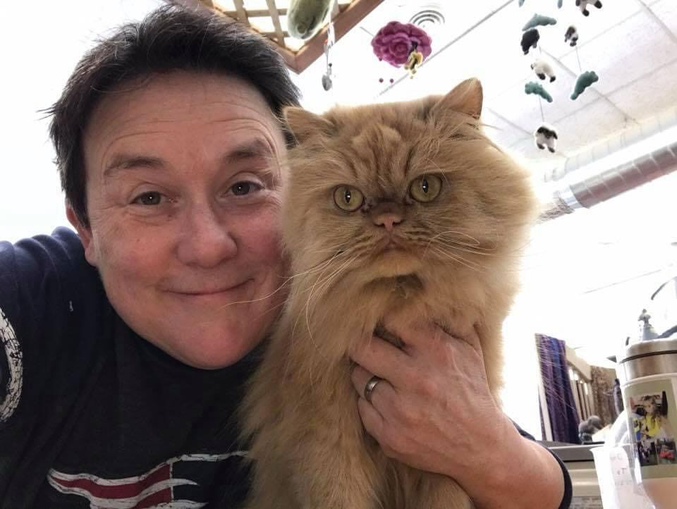 A woman is holding a fluffy orange cat in her arms.