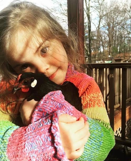 A little girl is holding a stuffed animal in her arms.