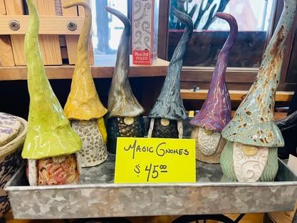 A display of ceramic gnomes with a yellow sign that says `` magic gnomes ''.