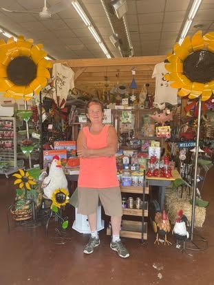 A man in a red tank top is standing in front of a store.