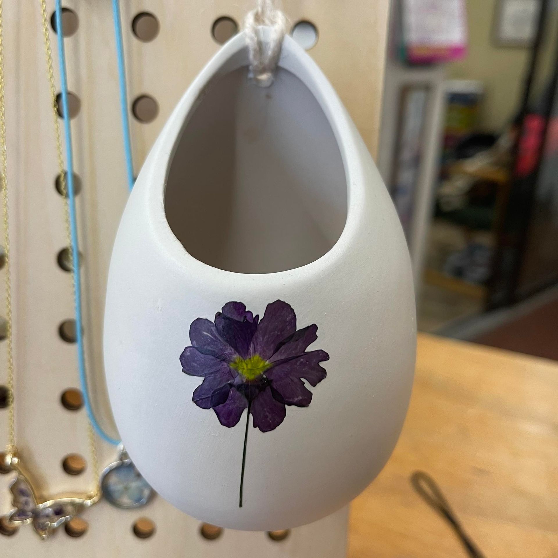 A white vase with a purple flower on it