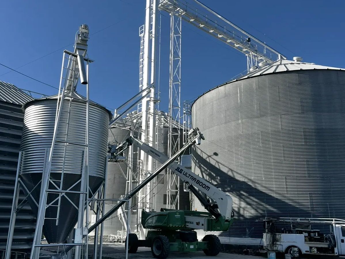 Grain storage facility with tall metal structures and silos against a blue sky