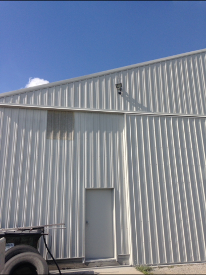 White metal building with a door and a blue sky.