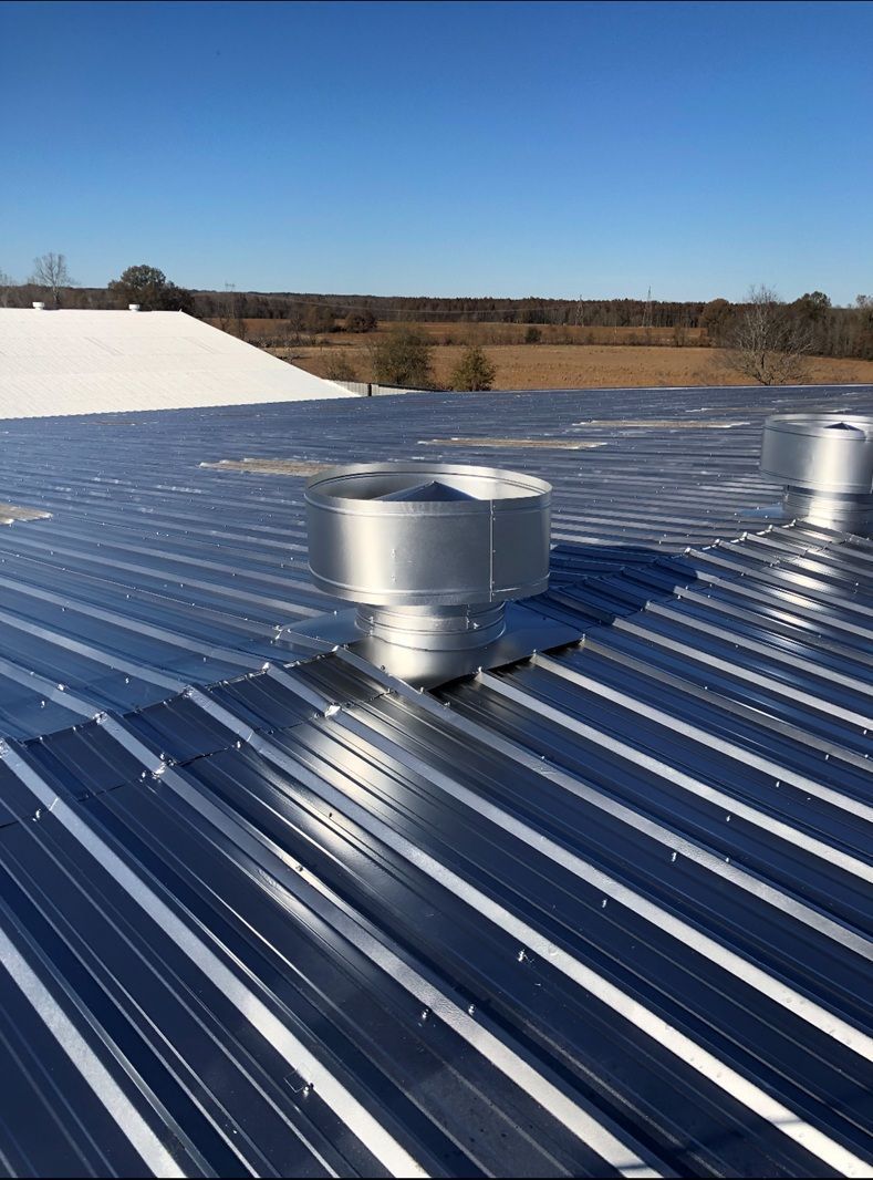Silver metal roof with vents under a clear blue sky.