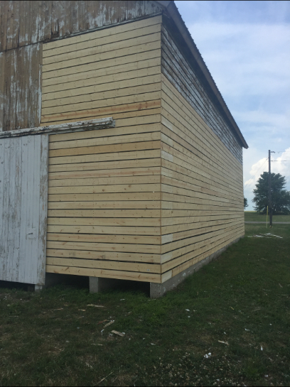 Barn with new wooden siding on a portion of the structure, old weathered siding on the other portions.