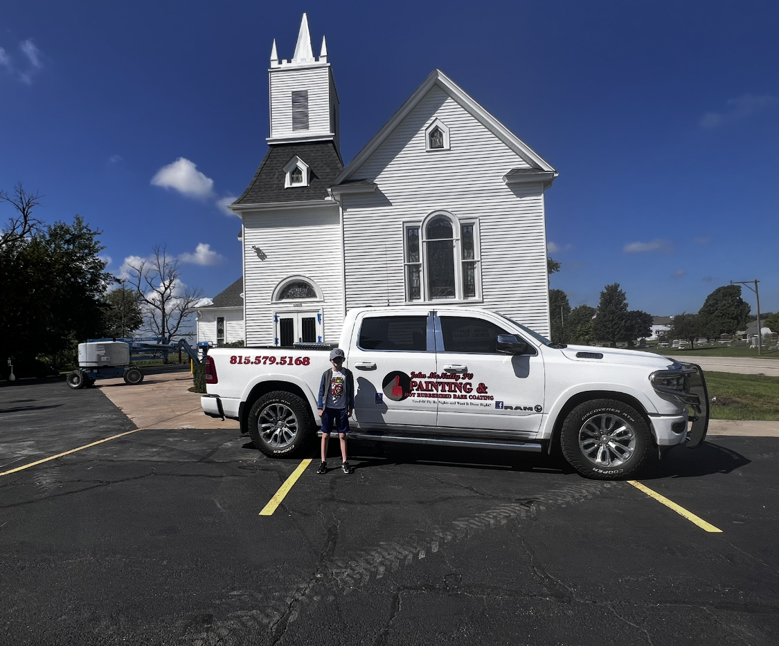 A white truck is parked in front of a white church.