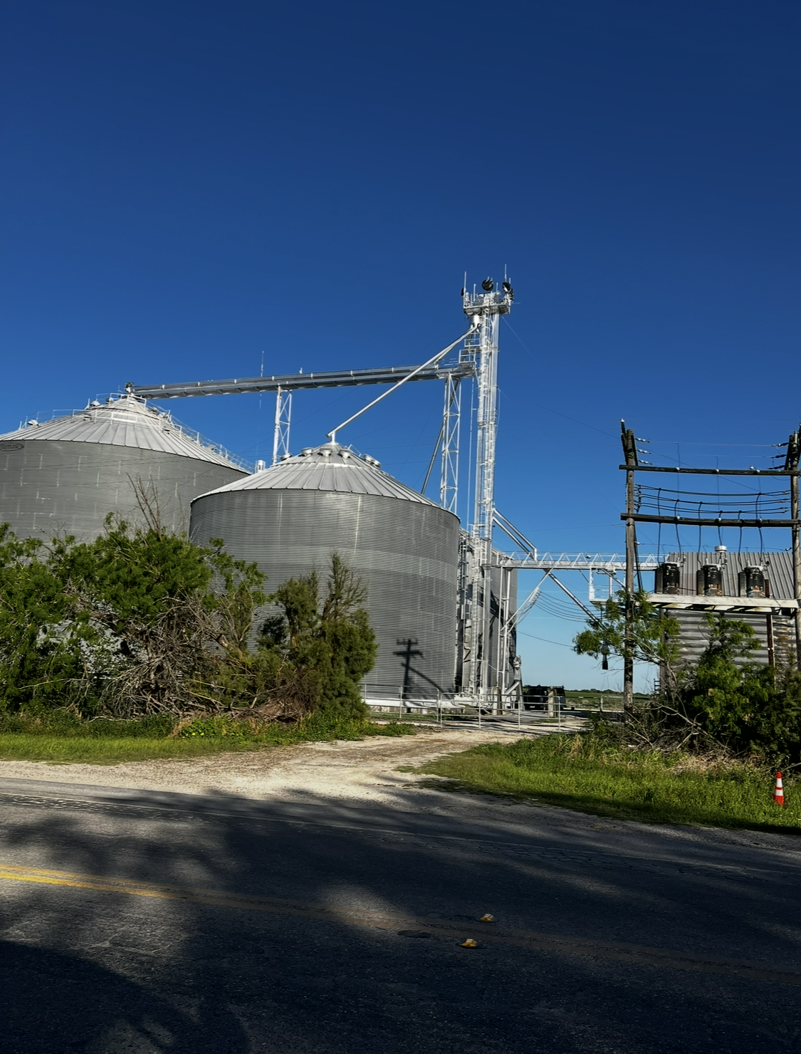 A large grain silo sits on the side of a road