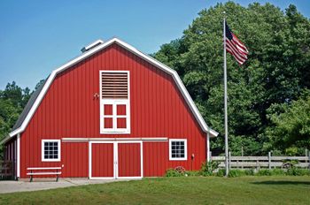 Red barn with white trim and an American flag on a sunny day.