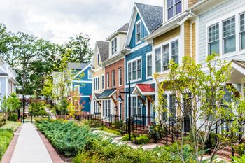 Row of colorful townhouses with sidewalks and landscaping.