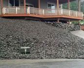 A large pile of gravel is in front of a house with a deck.