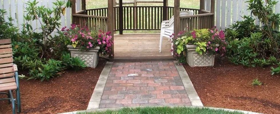 A gazebo with a brick walkway leading to it