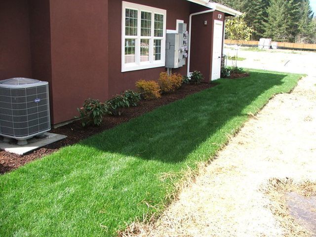 A brown house with a lush green lawn in front of it