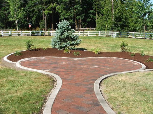 A brick walkway going through a grassy field