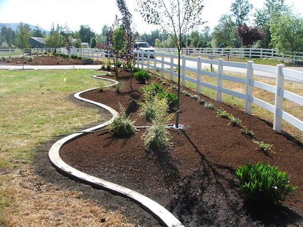 A white fence surrounds a lush green yard