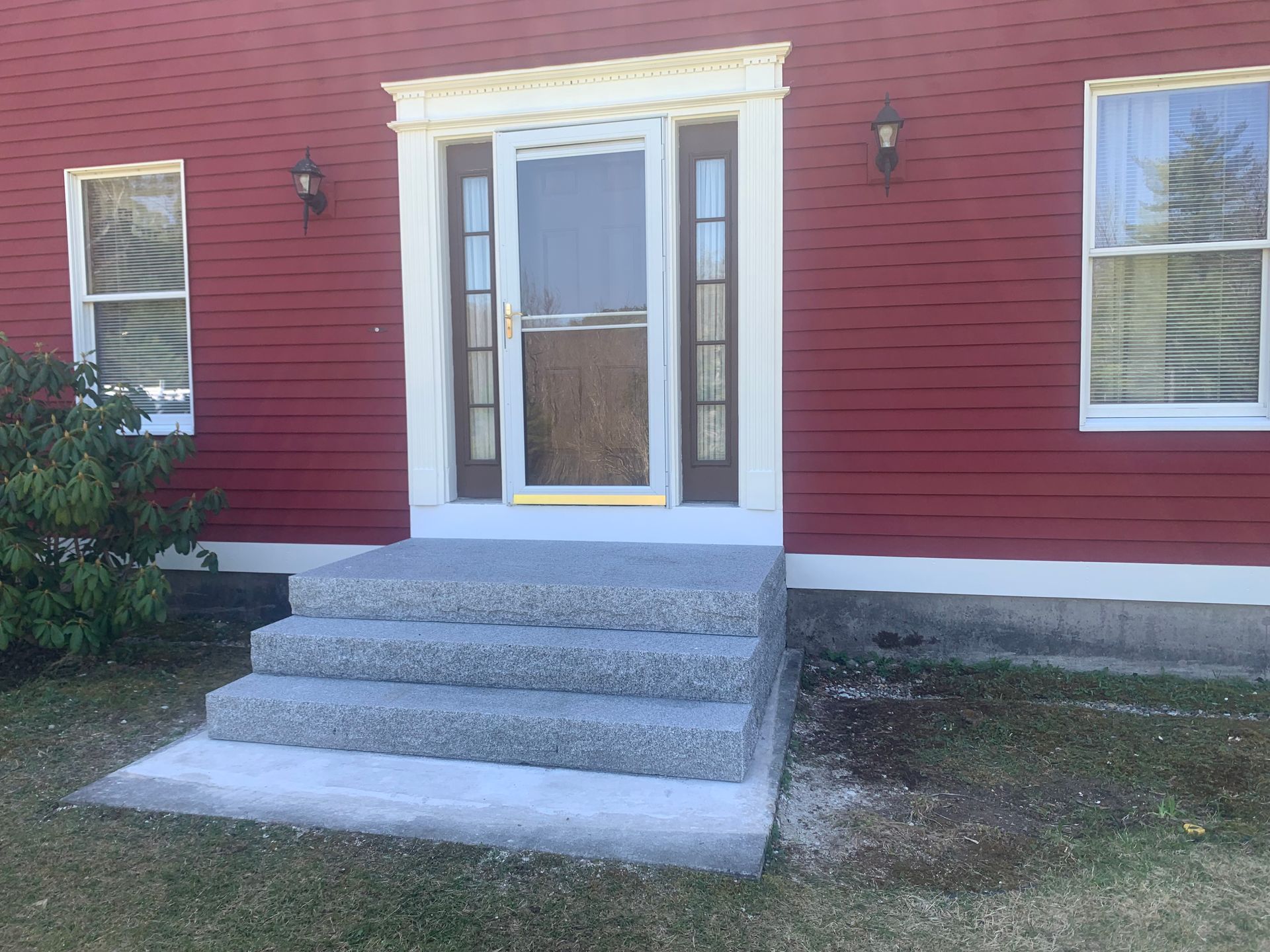 Red house with concrete steps leading up to the front door.