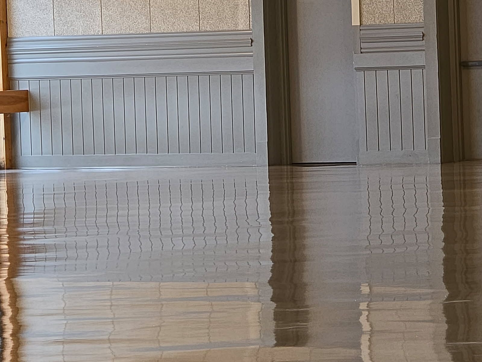 A room with a reflection of a door in the floor