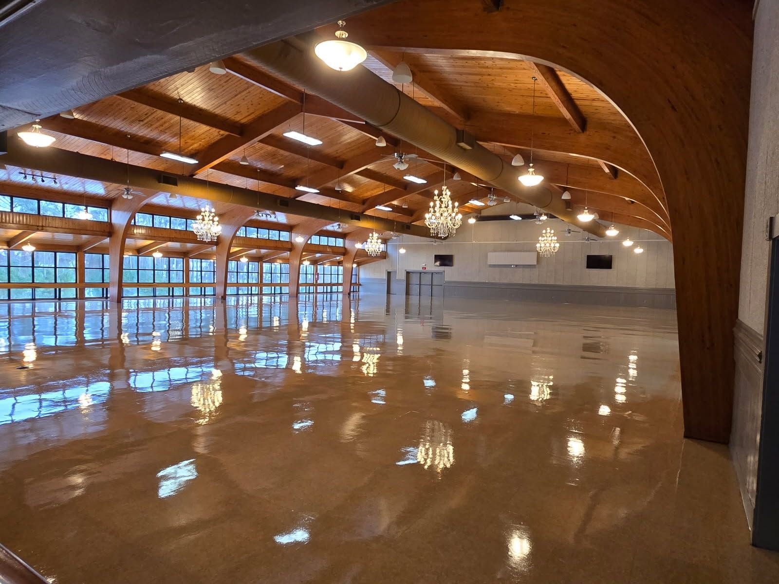 A large empty room with a wooden ceiling and lots of windows