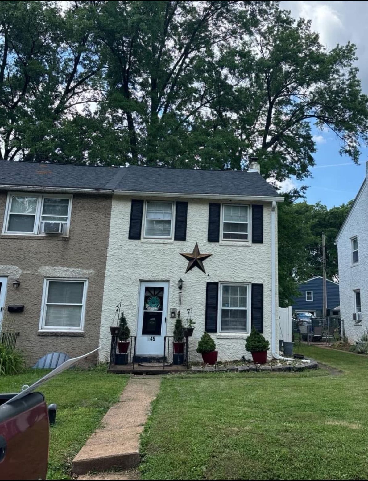 Two-story white house with black shutters and a star decoration. A path leads to the front door.