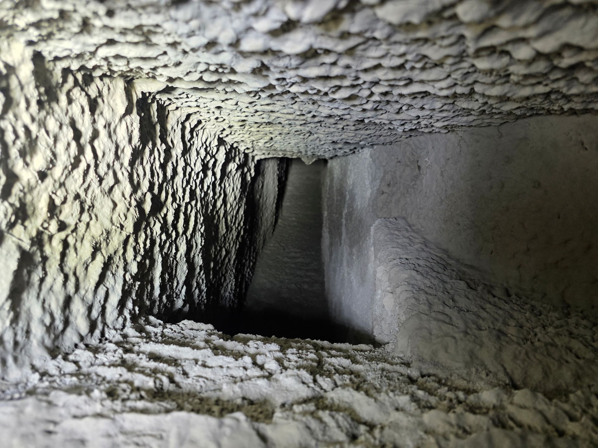 Chimney stack on a roof, orange brick with gray slate tiles and wooden scaffolding.