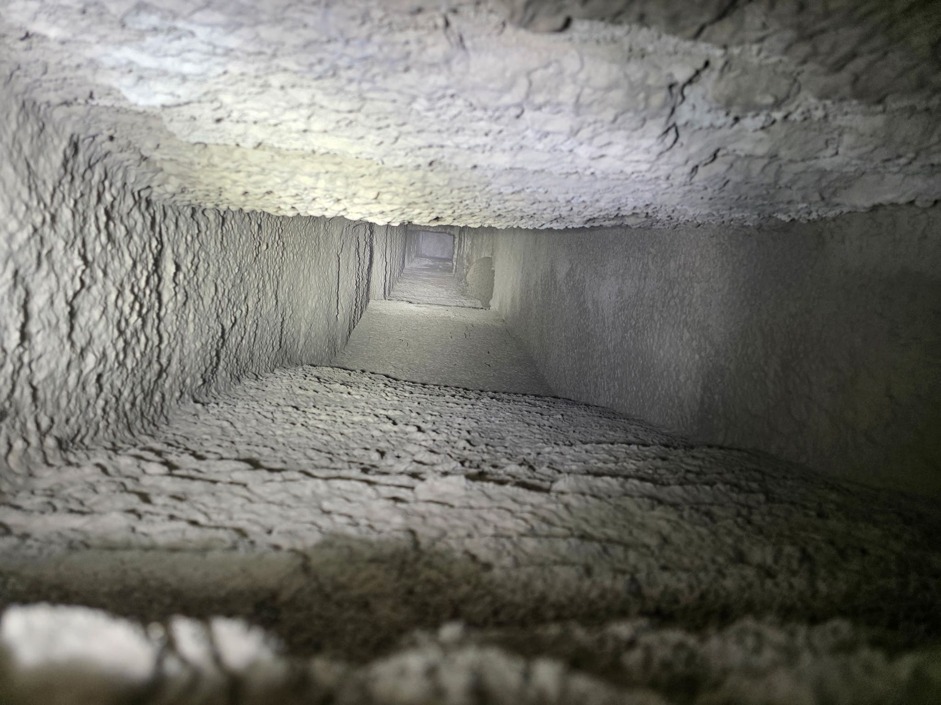 Dust-filled air duct interior, square shaped, showing buildup.