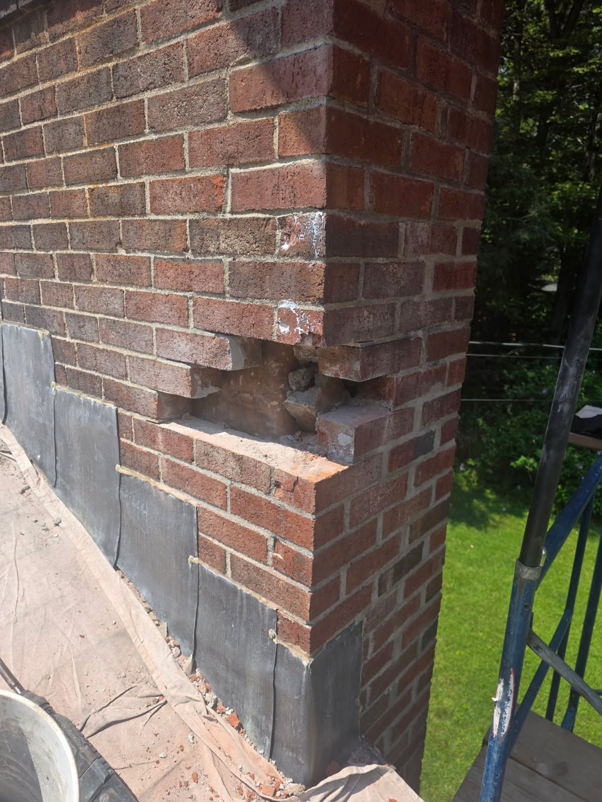 Exterior brick chimney base on a residential home showing masonry detail near the foundation.