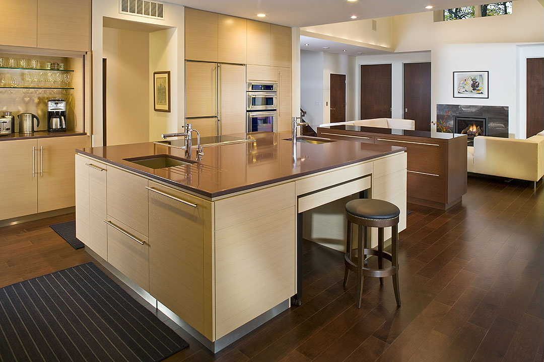 Modern kitchen with large island, light cabinets, dark wood floors, and seating.